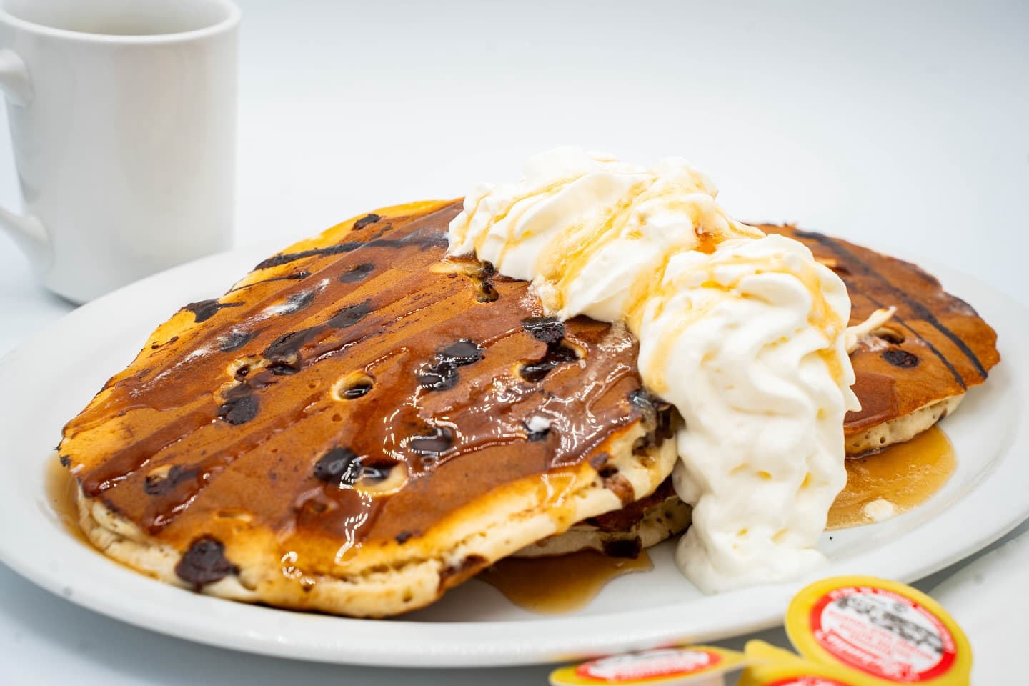 Chocolate pancakes topped with whipped cream and syrup